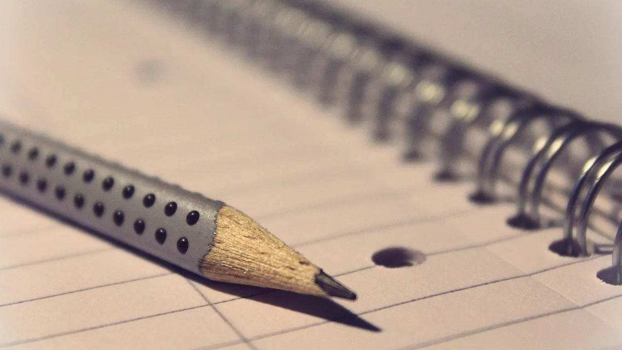 La pointe d’un crayon posée sur du papier quadrillé, sans rien écrire